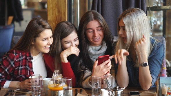 Four Friends Look at the Phone and Laugh