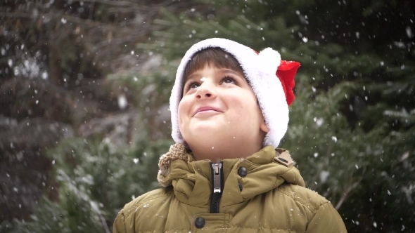 a Child in a Santa Claus Hat Rejoices in the Falling Snow