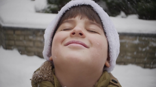 Snowflakes Fall on the Face of a Boy Who Smiles