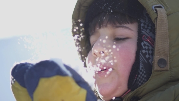 Boy Blows Snow From the Palms of His Hands