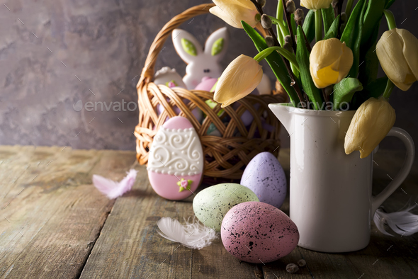 tulip flowers bouquet in pitcher and easter eggs in front of wooden wall