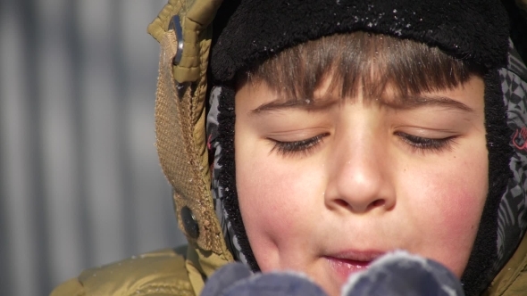 the Boy Squeezes His Eyes and Blows the Snow From His Palms