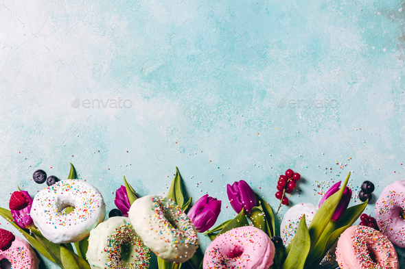Sweet and colourful doughnuts with sprinkles, purple tulips and - Stock Photo - Images