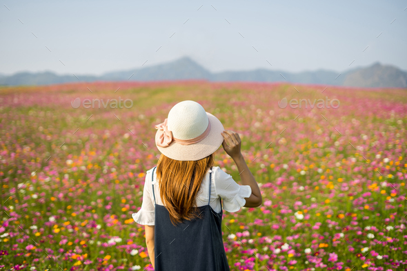 Young woman traveler looking beautiful flowers field Stock Photo by kitzstocker