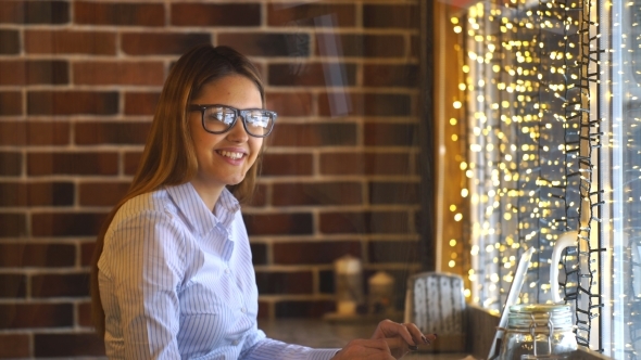 Woman Working with Laptop in Cafe, Smiling and Looking at the Camera