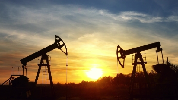 Working Oil Pumps Silhouette Against Sunset alt