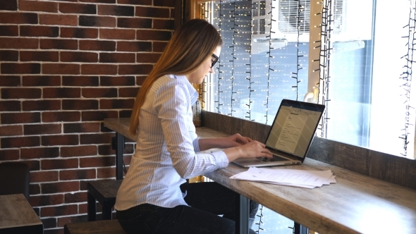 Businesswoman Working on a Computer in a Cafe and Studying Documents