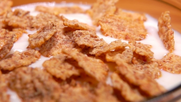 Cereal Flakes Falling Into a Glass Bowl with the Yogurt alt