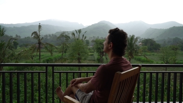 Man Relaxing on Balcony with Beautiful Mountain View on Vacation at the Hotel Apartment Terrace