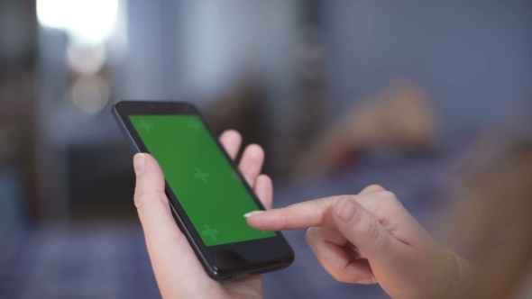 Woman Is Holding Smartphone with Green Screen in Home