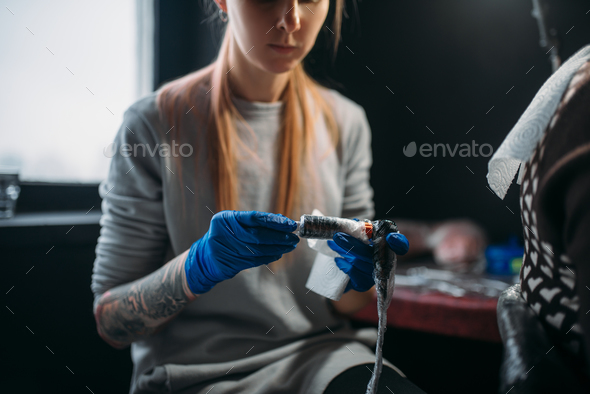 Female tattooist prepares tattoo machine - Stock Photo - Images
