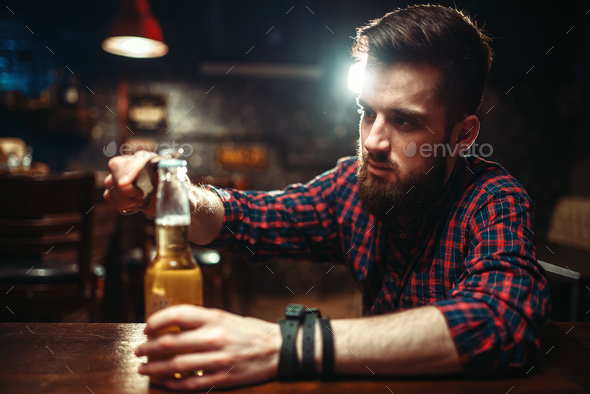 Man sitting at the bar counter and opens bottle - Stock Photo - Images