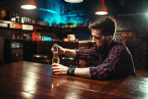 Man sitting at the bar counter and opens bottle - Stock Photo - Images