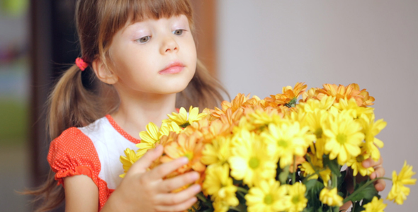 Small Girl Looking at Bunch of Yellow Flowers