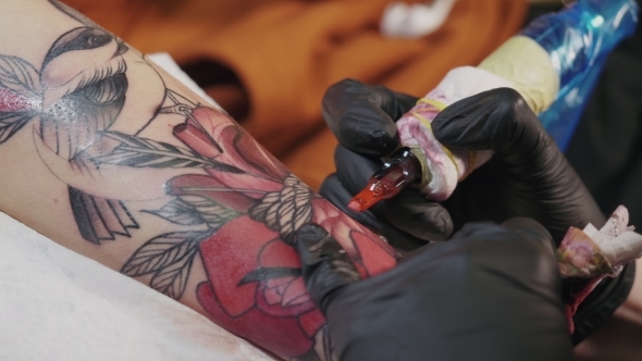 The Tattoo Artist at Work. A Girl Holding a Machine and Applied in ...