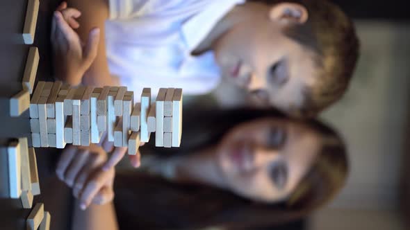 Mother and Son Playing in Board Game with Wooden Tower at Home