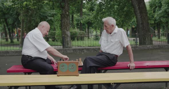 Two Nice Seniors Men Playing the Chess Game Using Clock and Having a Talk alt