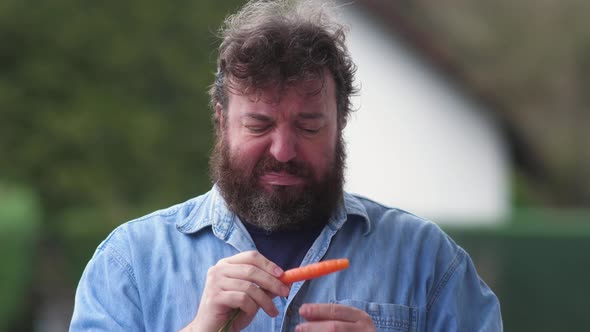 Bearded man is skeptical about fresh carrot and healthy diet. Concept idea