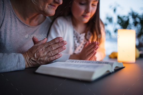 A small girl and grandmother praying at home. - Stock Photo - Images