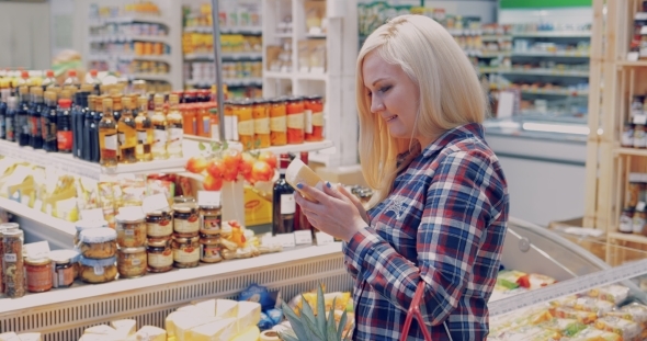 Young Woman Chooses Cheese in the Big Store alt