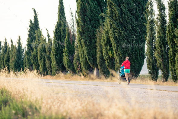 Mother runner with baby stroller jogging at sunset landscape - Stock Photo - Images