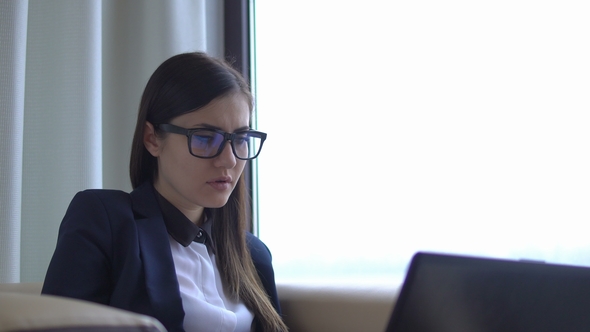 Young Brunette Businesswoman in Office Suit Works with Laptop.