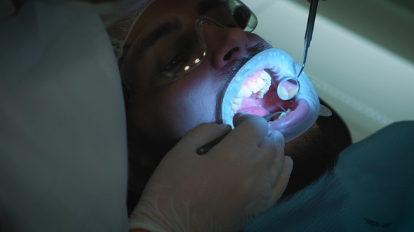 Dentist at Work in the Office A Female Doctor Examines the Teeth and Jaws of a Male Patient