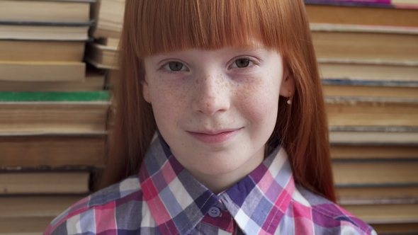 Face of a Little Happy Schoolgirl on Background of Books