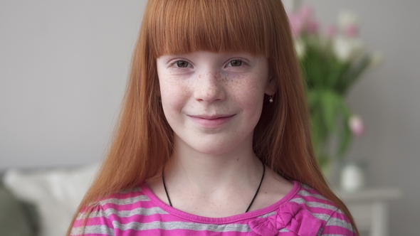 Little Happy Ginger Girl with Freckles Smiling in a White Room