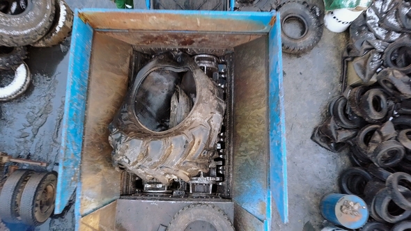 The Old Car Tire in the Shredder at the Waste Recycling Plant alt