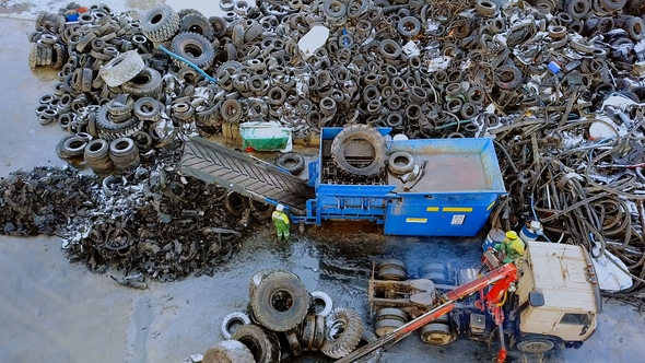 Waste Recycling Plant. The Truck Crane Loads Old Tires Into the Shredder for Recycling alt