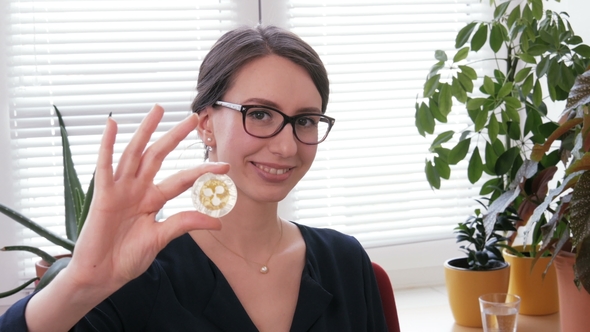 Young Woman Shows a Golden Ripple Coin in Hand at Camera