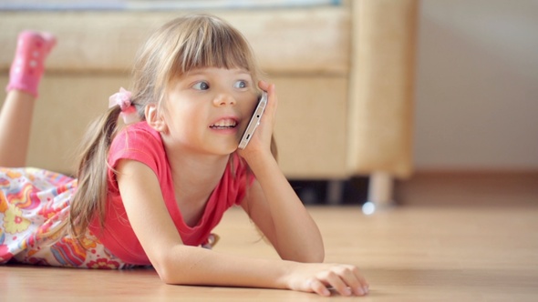 Small Girl Talking on Smartphone Lying on Floor