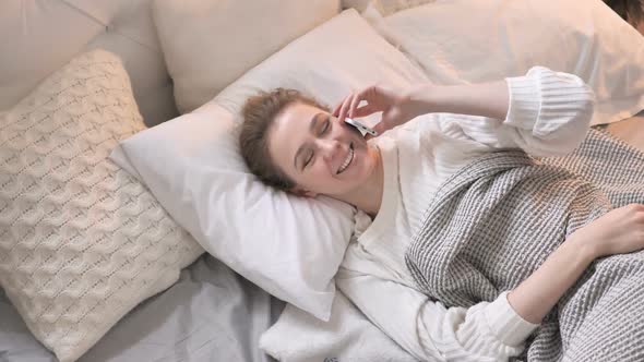 Top View of Young Girl Talking on Phone in Bed alt