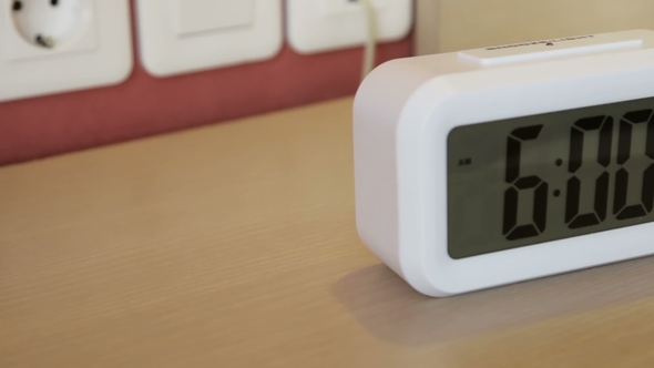 Electronic Alarm Clock Stands on a Bedside Table in the Room