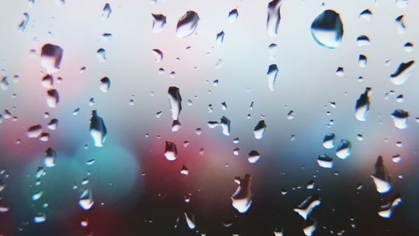 Drops of Rain on Glass on Background of Colored Lights