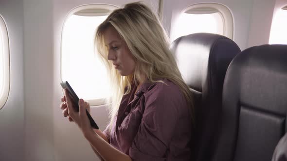 Young woman using digital tablet on airplane flight