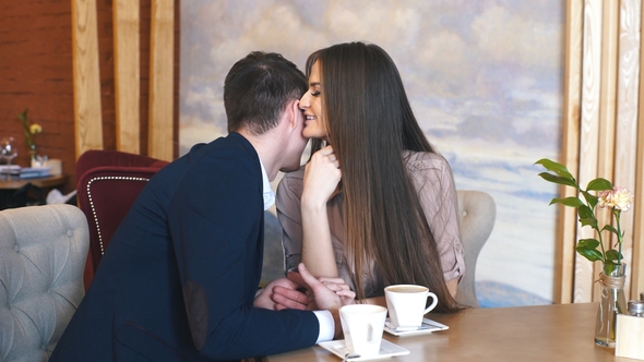 Flirting in a Cafe. Beautiful Loving Couple Sitting in a Cafe Enjoying in Coffee and Conversation
