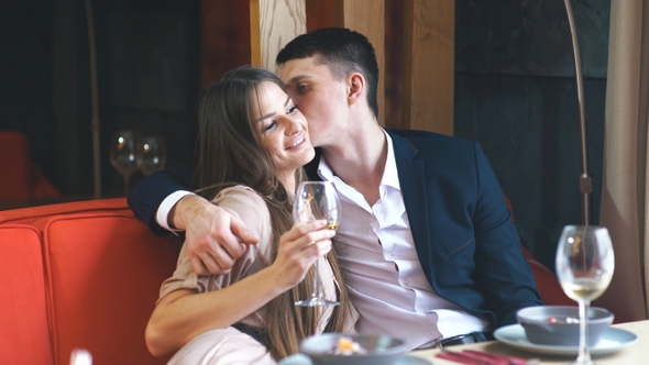 Smiling Couple Having Dinner and Drinking White Wine at Date in Restaurant