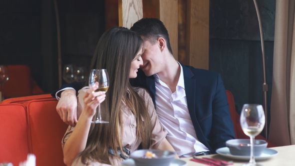 Beautiful Young Couple with Glasses of Wine in Luxury Interior