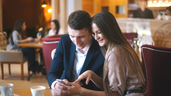 Embracing Couple Using Mobile Phone in Cafe