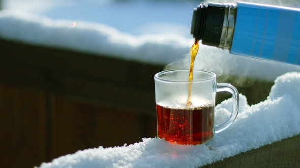 Tea Pour Down To Glass Standing on Snow at Tree Branch