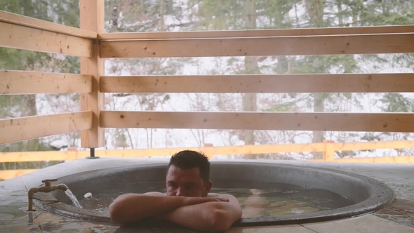 A Man Is Bathing in the Cast Iron Vat with Mineral Water and Turned Off the Tap with Cold Water. alt
