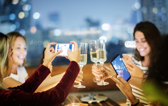 Girl friends having a dinner together at a rooftop bar taking a - Stock Photo - Images