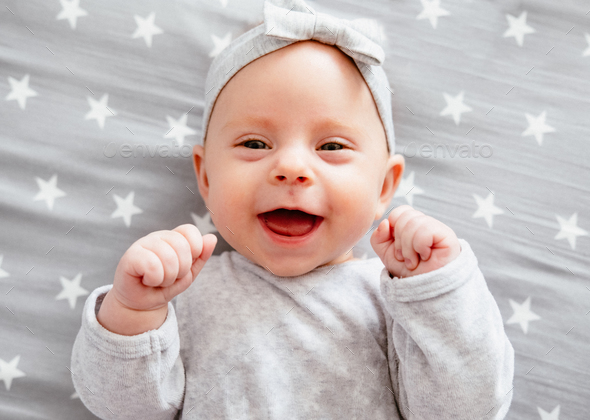 Happy laughing baby girl on her bed. - Stock Photo - Images