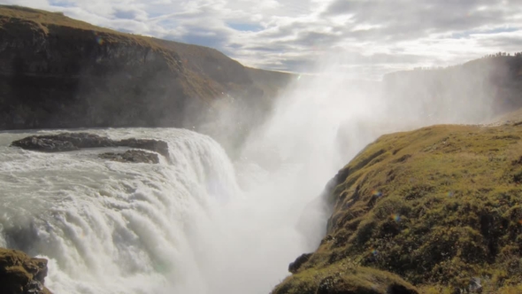 Amazing Large Waterfall in Sunny Day in Iceland, Splashes Are Flying Up, Cloudy Sky in Background