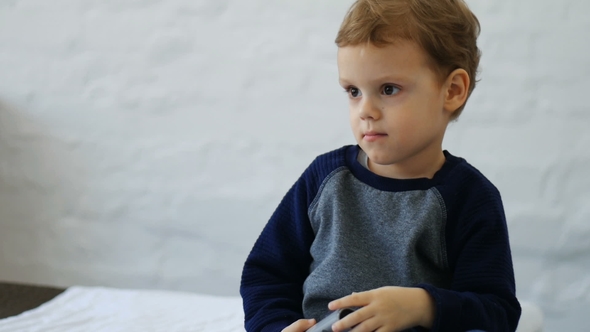 Happy Baby Boy Playing with TV Remote Controller on the Chair