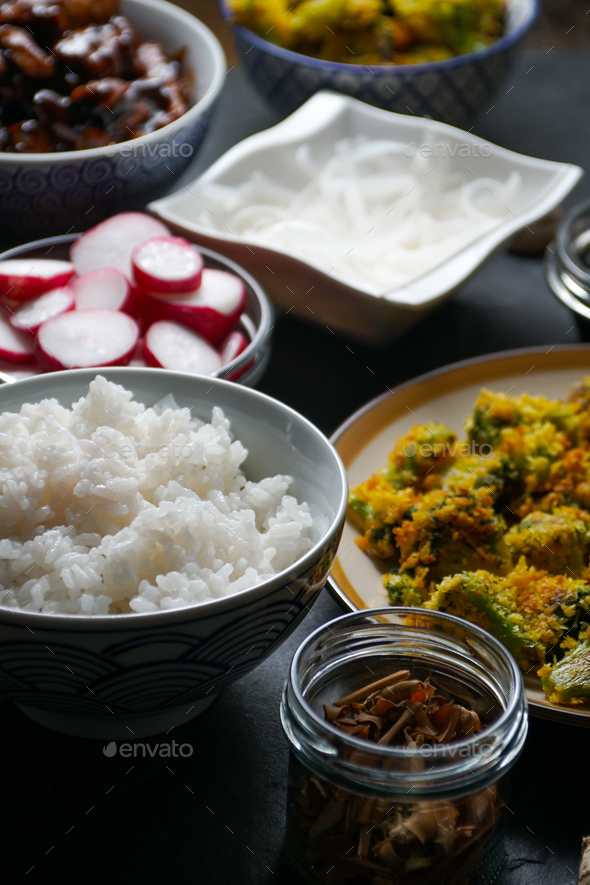 Pieces of teriyaki chicken, rice vermicelli and tempura broccoli on the table. Stock Photo by Deniskarpenkov