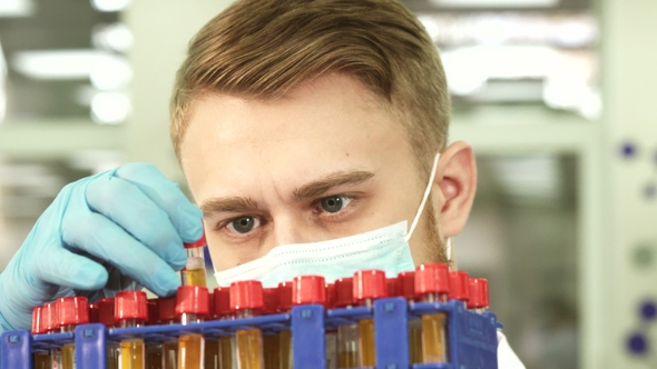 A Serious Lab Technician Studies Test Tubes with Assays alt