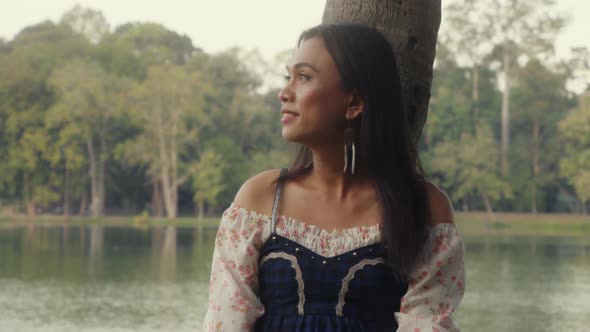 Transgender Asian Woman Leaning Against a Tree in the Park Enjoying the Moment alt